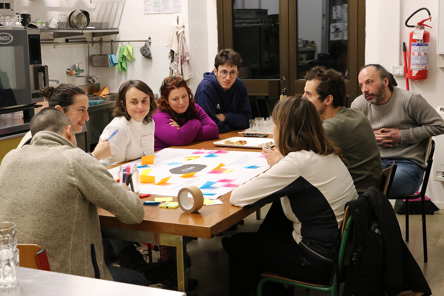 A kitchen table around which eight people brainstorm on issues relate to food.