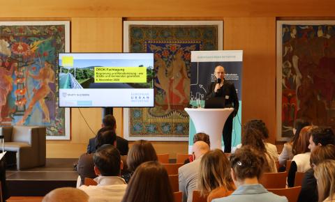 Präsentator vor Bildschirm