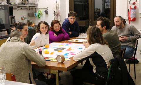 A kitchen table around which eight people brainstorm on issues relate to food.
