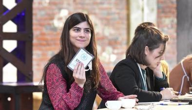 Weibliche Person an einem Tisch mit Karte in der Hand